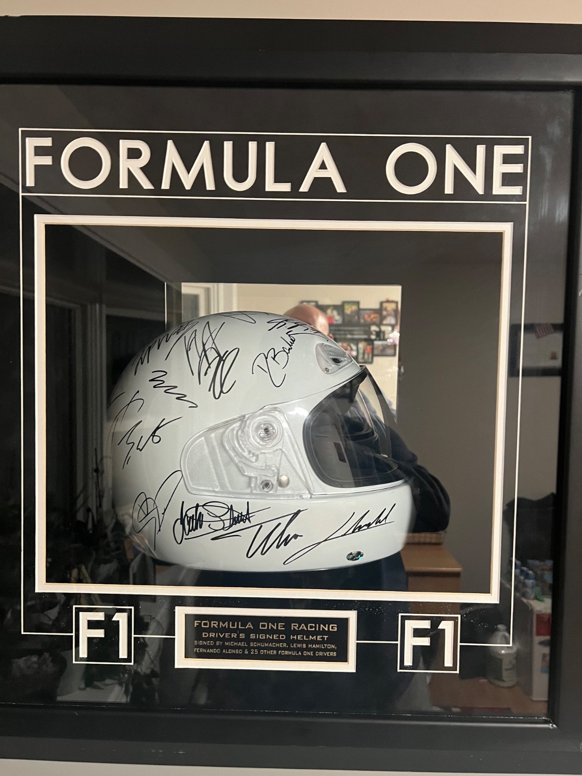 Framed Formula 1 memorabilia featuring a signed white helmet