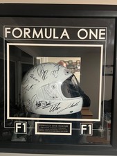 Framed Formula 1 memorabilia featuring a signed white helmet picture